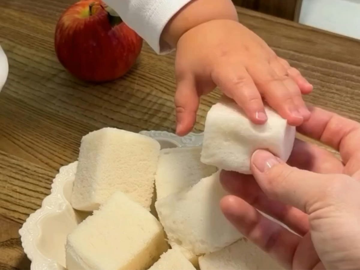 mão de bebe pegando sobremesa de nuvem de maçã